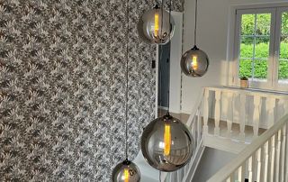 hall escalier avec papier peint à motifs et luminaires en verre soufflé