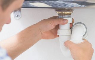 plombier qui répare un lavabo