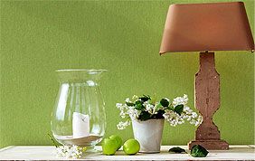 lampe et bibelots devant un mur tapissé en vert
