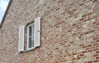 volets battants blancs sur façade en briques