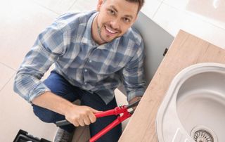 plombier souriant qui répare une canalisation