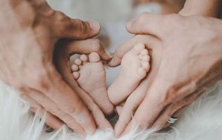 mains des parents tenant les pieds de leur bébé