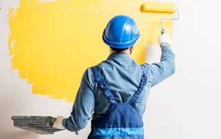 peintre appliquant de la peinture jaune au rouleau