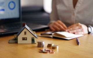 Professionnelle avec un carnet, une maison miniature et des pièces de monnaie