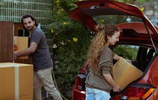 un couple charge une voiture de cartons