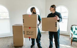 Deux déménageurs portent des caisses en carton