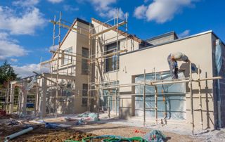 ouvrier sur un échafaudage et qui rénove une façade