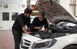 deux garagistes Auto Torino réparant un moteur