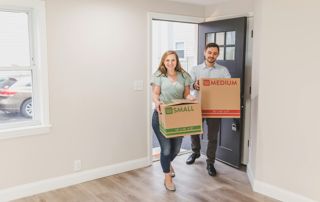 un couple amène ses cartons dans une maison