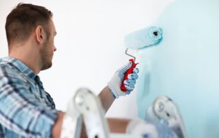 peintre qui applique de la peinture bleue ciel au rouleau