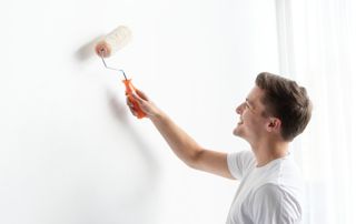 Peintre avec un rouleau de peinture blanche