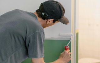 un peintre réalise les finitions avec un petit rouleau