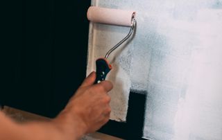 application peinture blanche au rouleau sur mur noir