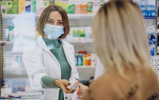 une pharmacienne tend un médicament à une cliente