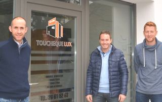 Trois homme posent devant la porte avec le logo de l'entreprise